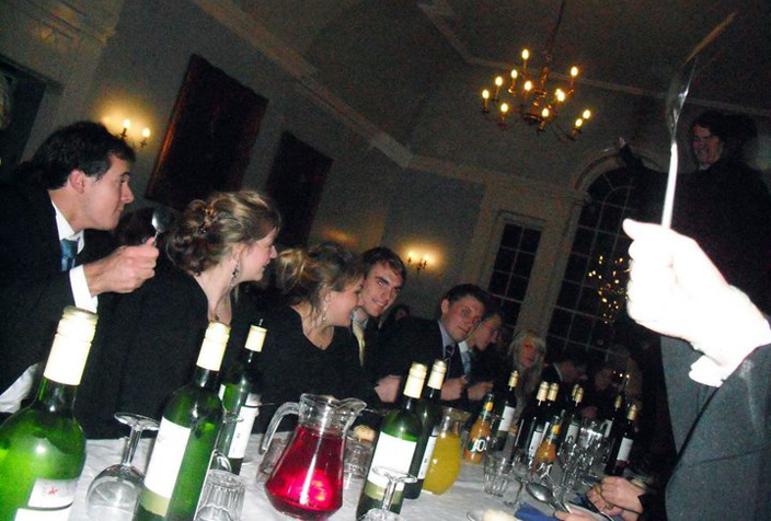 The Hatfield dining room in use at a college formal dinner. The students in this photo are spooning, a college tradition where the undergraduate students call the members of the Senior Common Room to dinner by banging their spoons on the table to different rhythms.